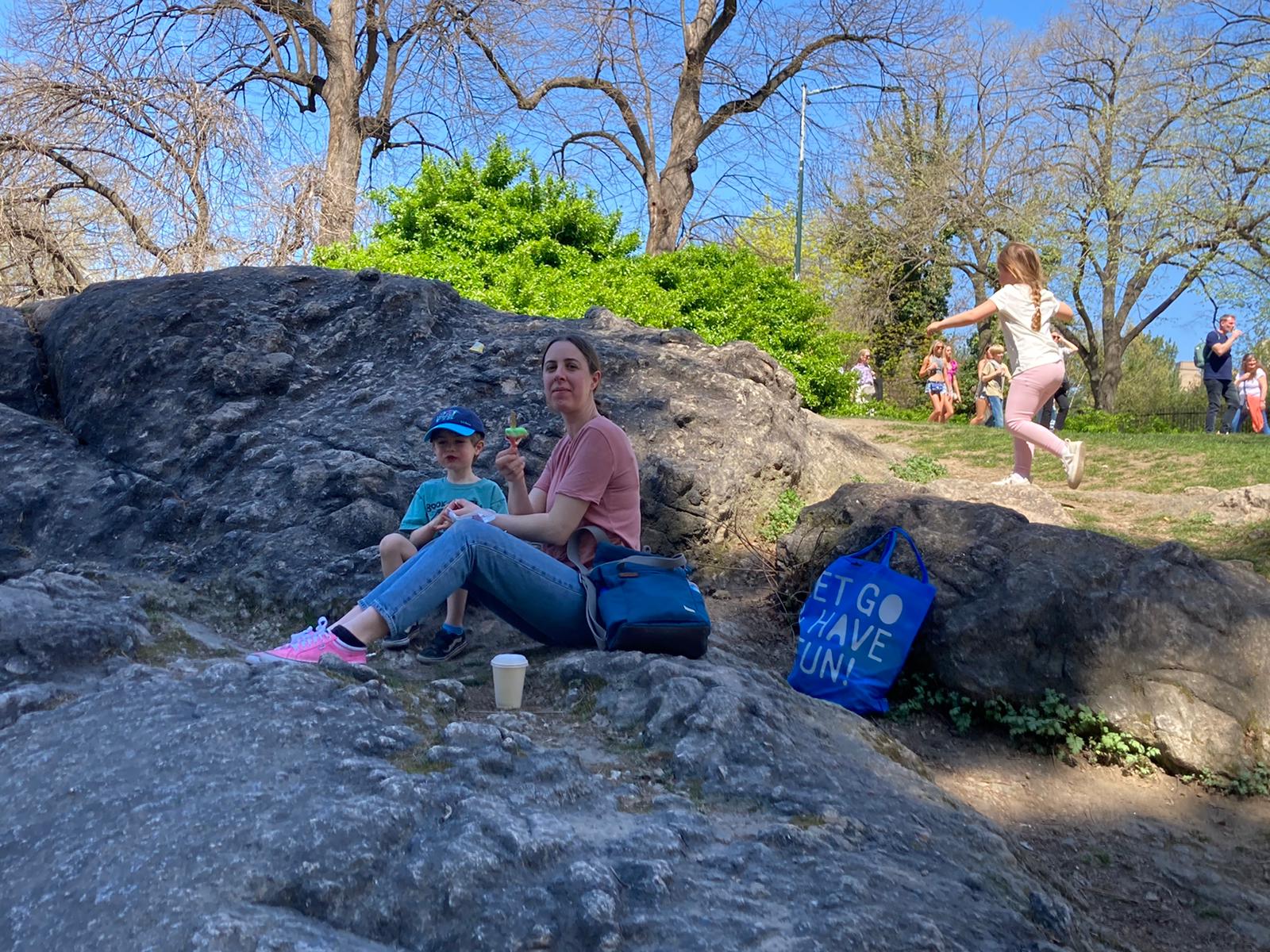 a photo of jess and her son sitting on a rock in central park